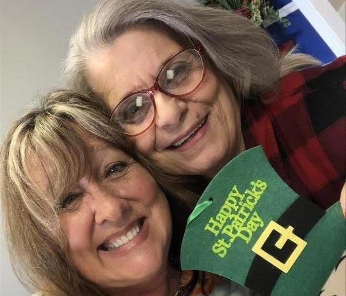 Two women posing for a picture with a St. Patrick's Day display