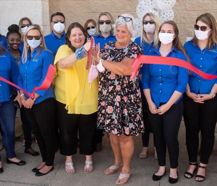 A large group of people standing around a ribbon cutting ceremony.