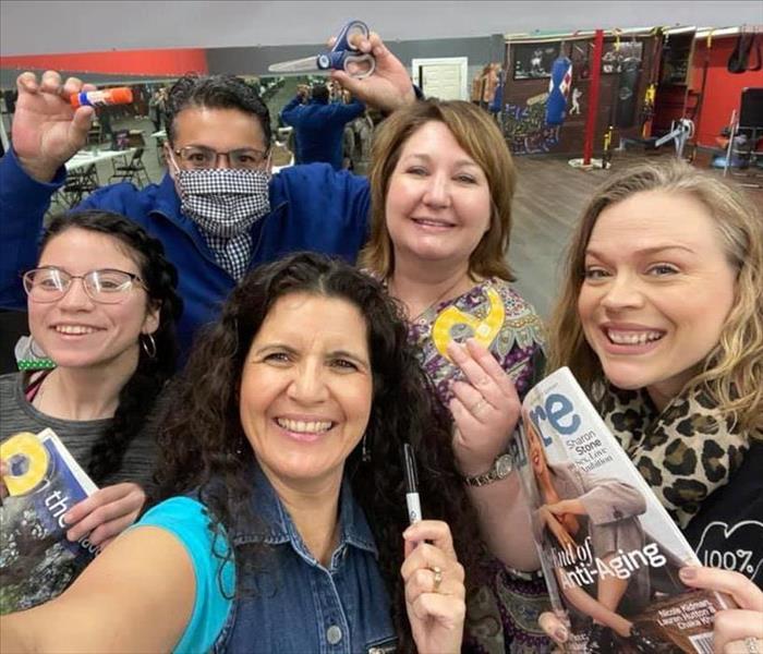 Group posing with magazines, tape, glue and markers 