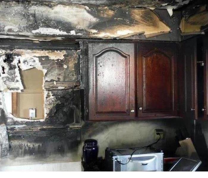 Burnt and charred appliances and kitchen utensils after a fire.